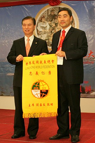 世界龙冈亲义总会刘盛良主席(左)赠送纪念锦旗给关公网站长关志杰（关乐声摄影） 