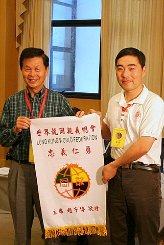 世界龙冈亲义总会赵守博主席(左)赠送印有“忠义仁勇”和龙冈会标的纪念锦旗（刘芳摄影）